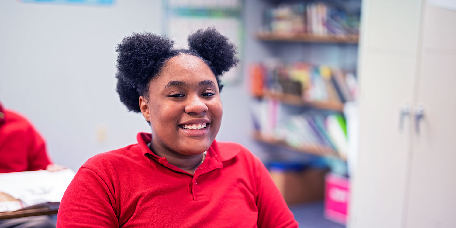 Smiling middle school student at a desk.